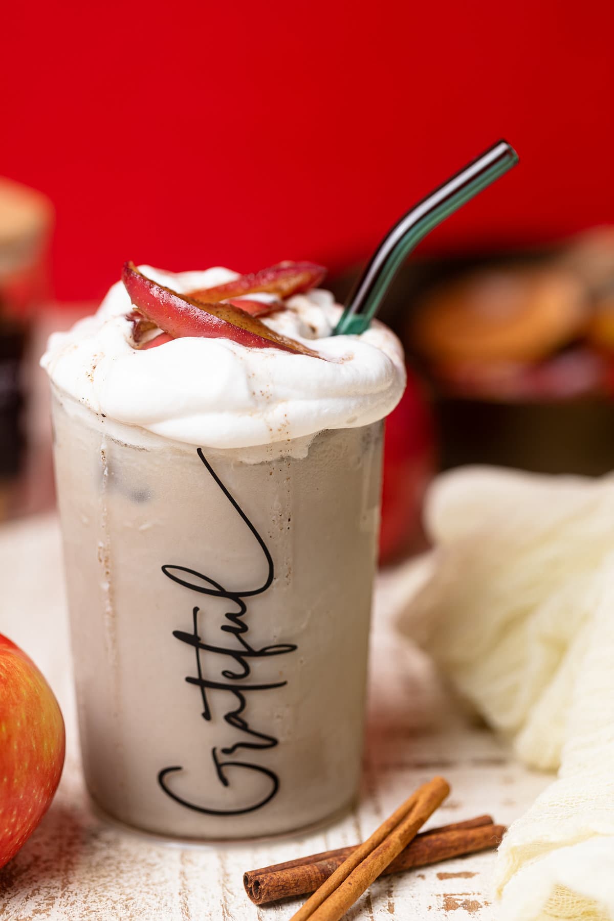 Overflowing Apple Crisp Oatmilk Latte in a glass that has \"Grateful\" written on it