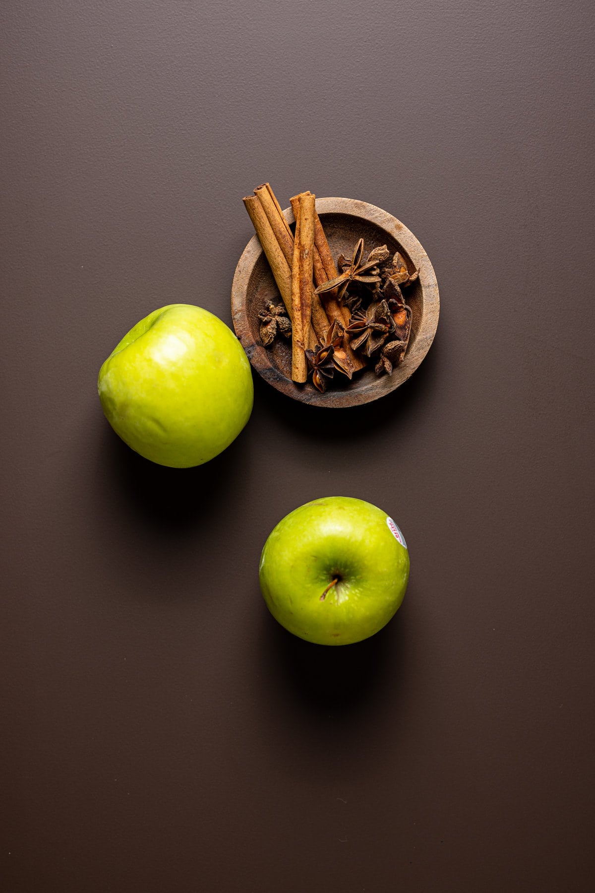 Bowl of spices next to two green apples