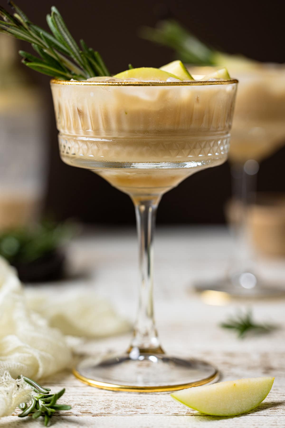 Apple Caramel Espresso Martini in a long-stemmed glass topped with a sprig of rosemary