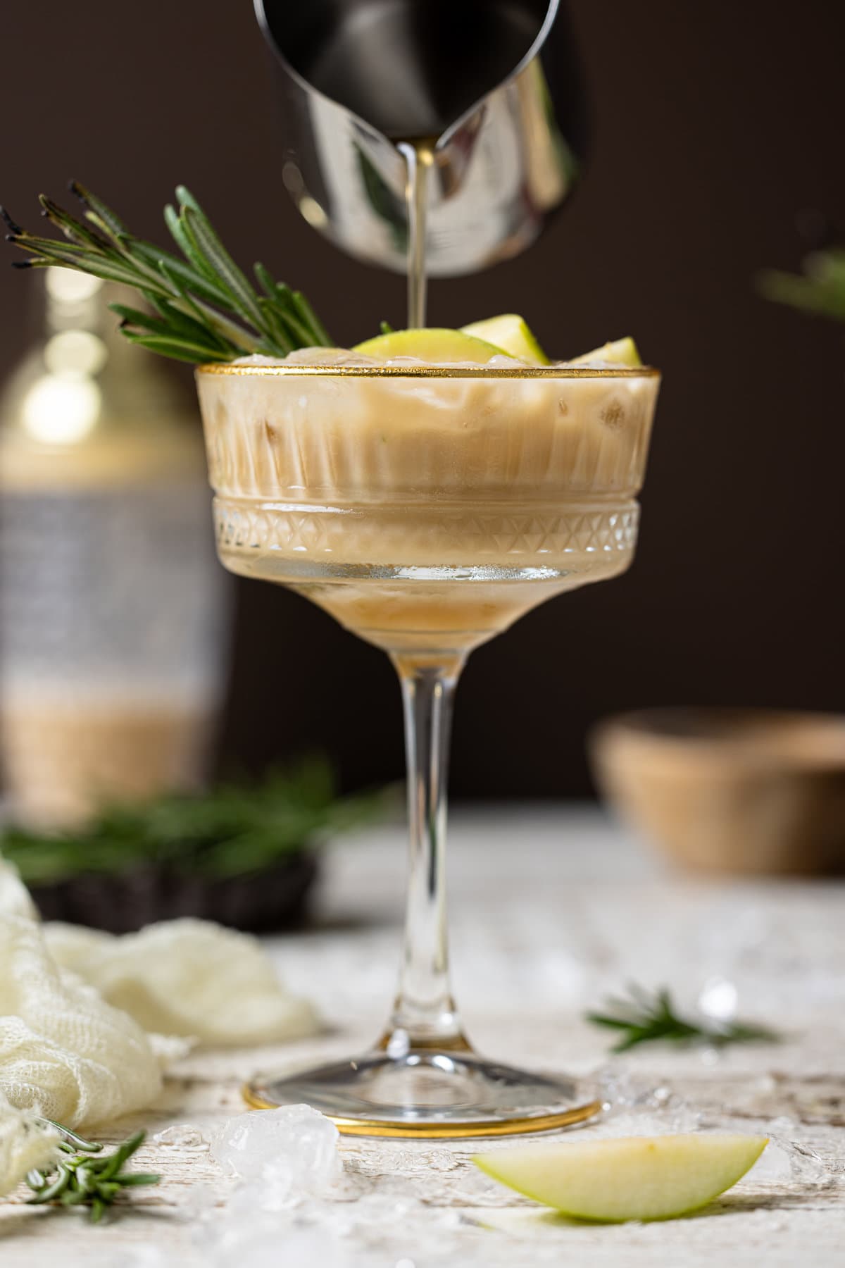 Apple Caramel Espresso Martini in a long-stemmed glass topped with a sprig of rosemary