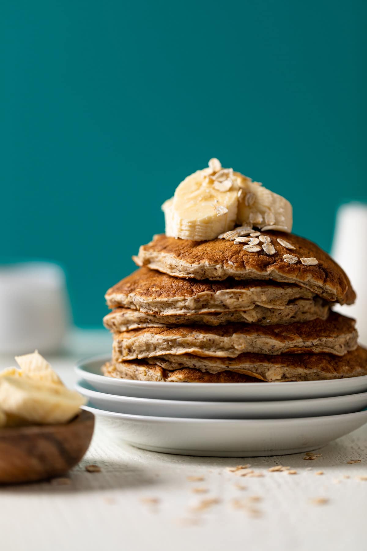 Stack of Fluffy Banana Oat Pancakes topped with banana slices