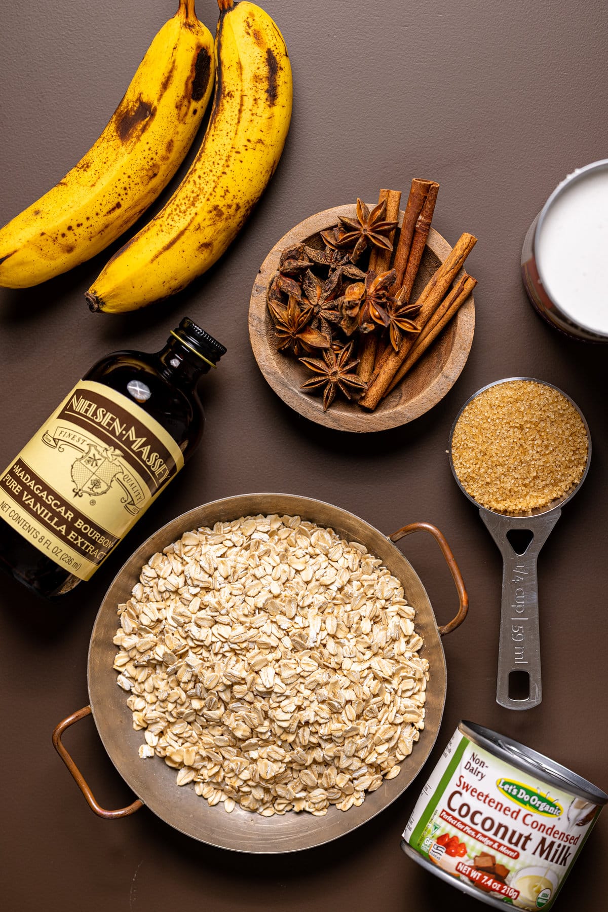 Ingredients for Banana Chai Oatmeal Porridge including cinnamon sticks, vanilla extract, and coconut milk