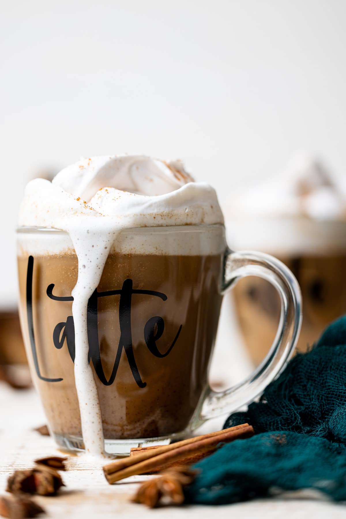 Overflowing glass of Fall Spice Latte with the word \"Latte\" on the side