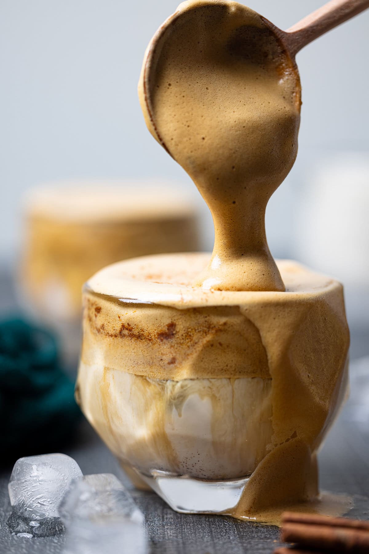 Spoon pouring foam into an Iced Dalgona Coffee Vanilla Latte