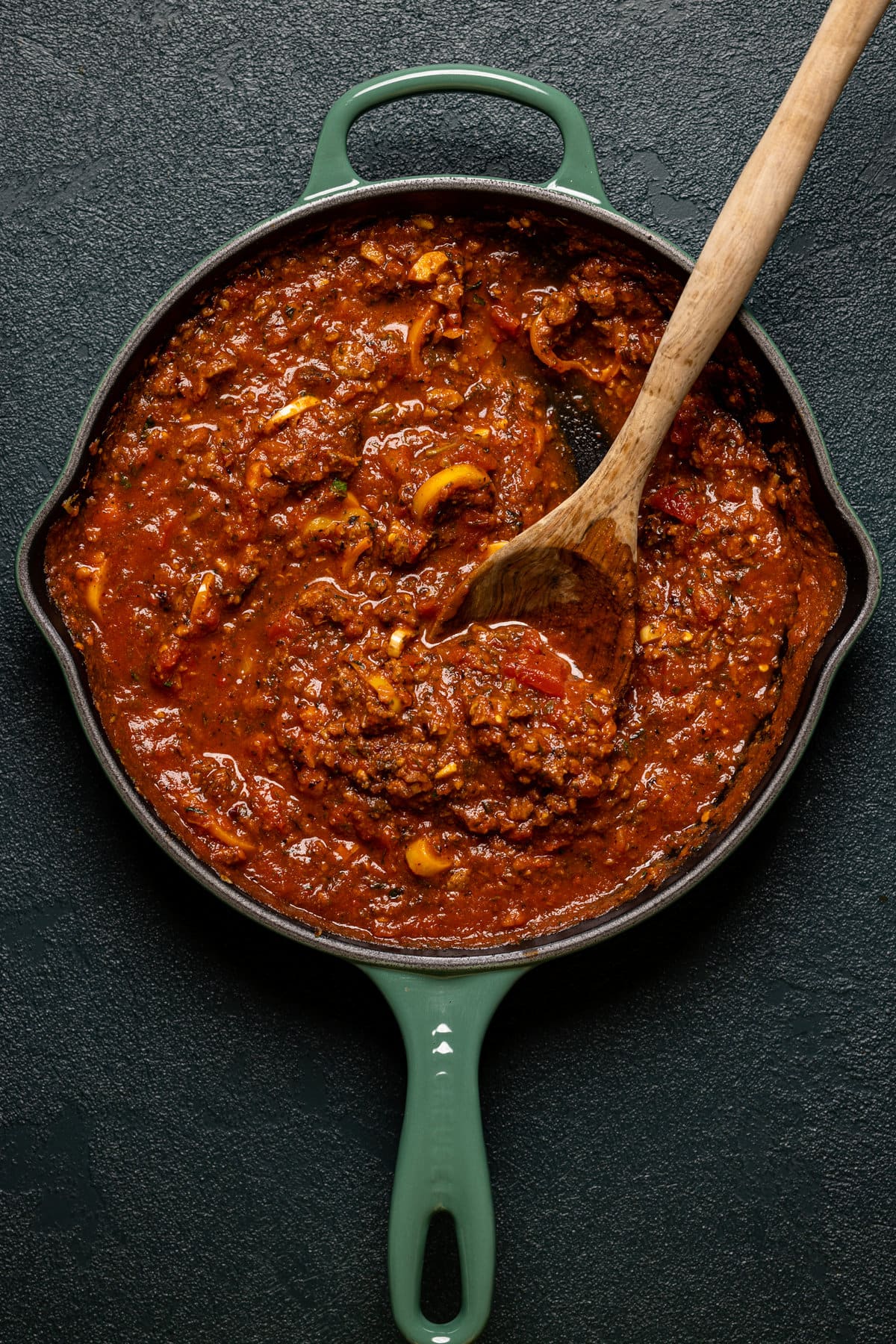 Wooden spoon stirring a skillet of Spicy Pumpkin Pasta sauce