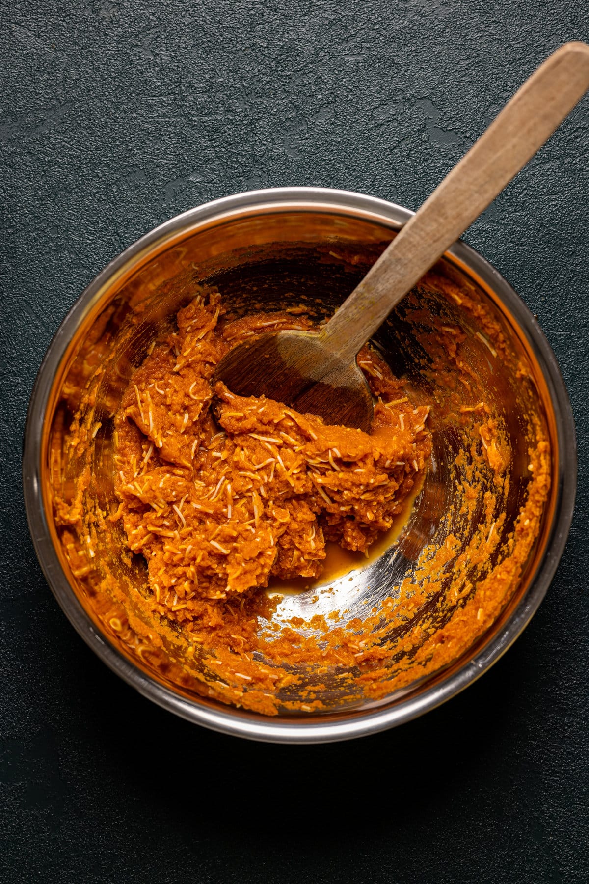 Wooden spoon stirring a bowl of pumpkin and cheese filling