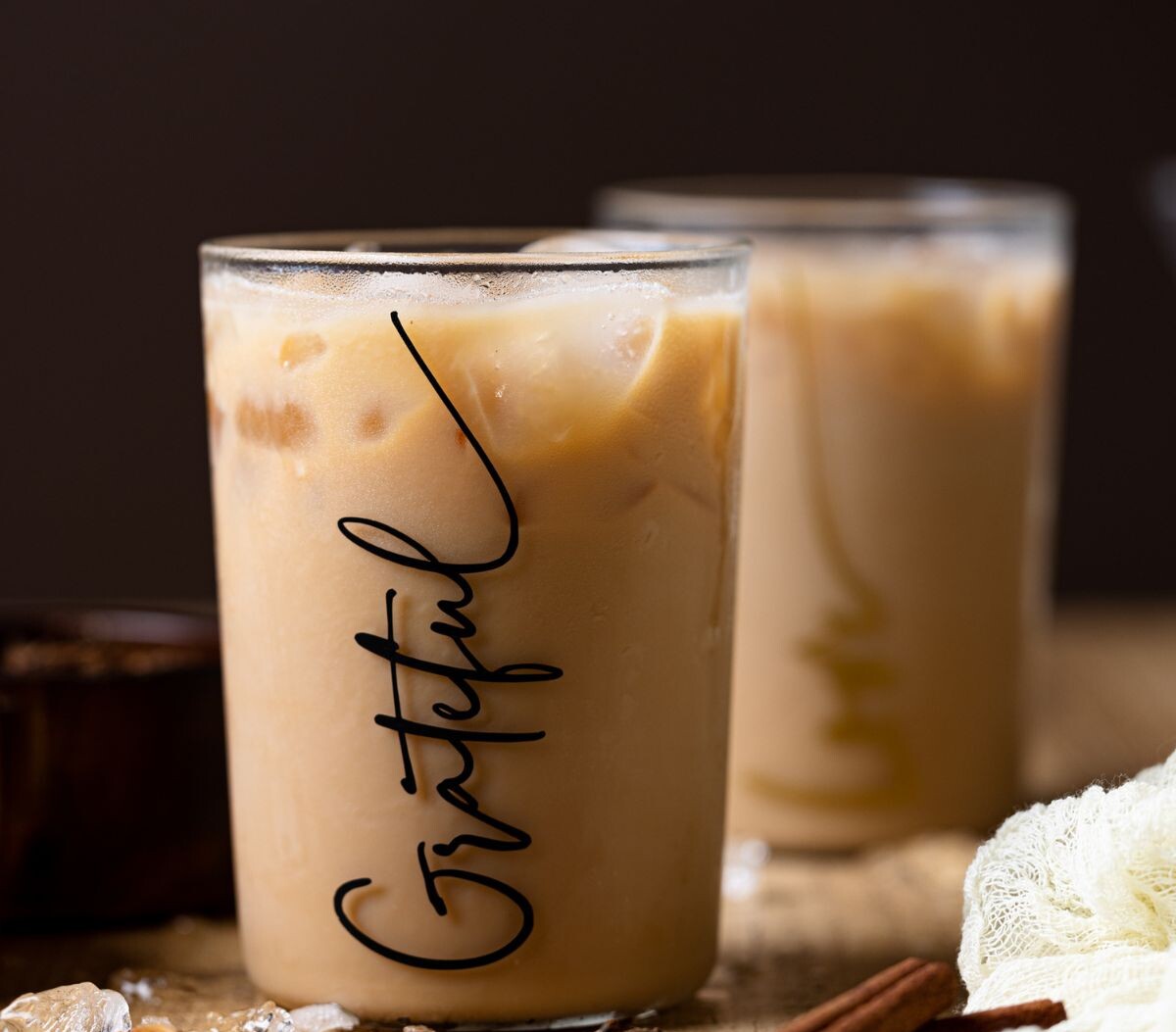 chai tea latte in a cup filled with ice on a brown wood table.