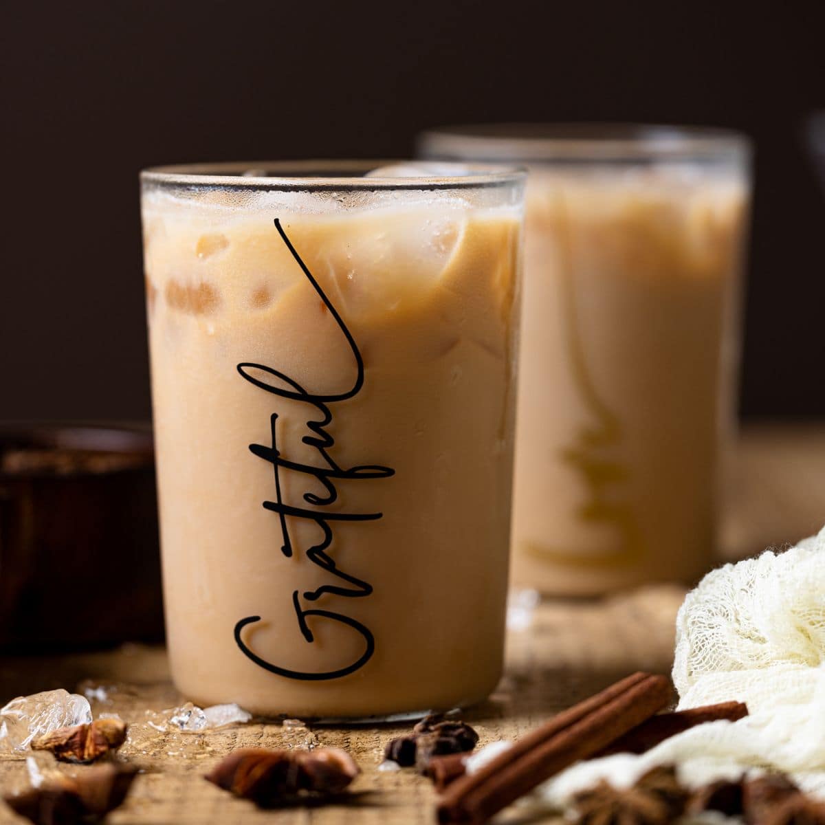 chai tea latte in a cup filled with ice on a brown wood table.
