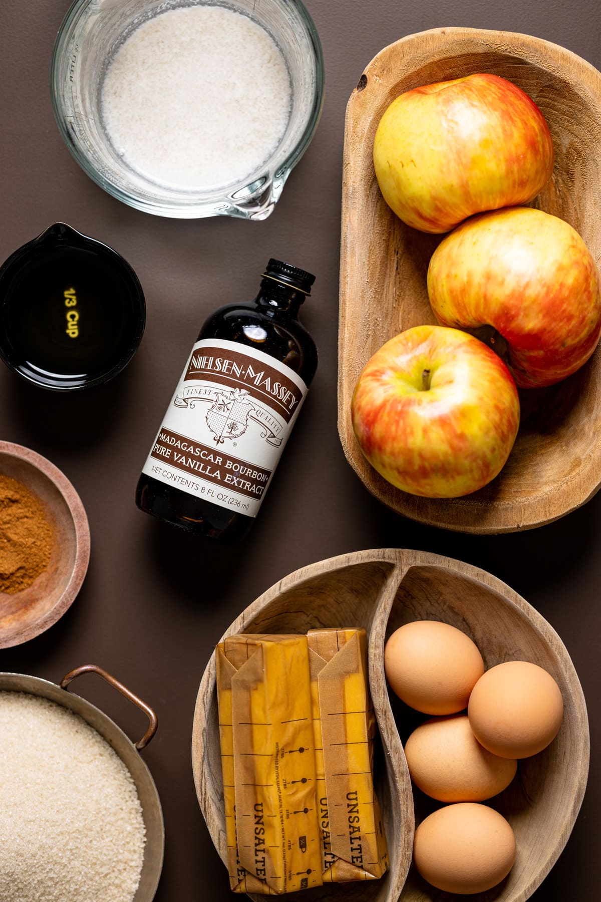 Ingredients for Apple Cider Cake with Cinnamon Maple Buttercream including eggs, vanilla extract, and apples