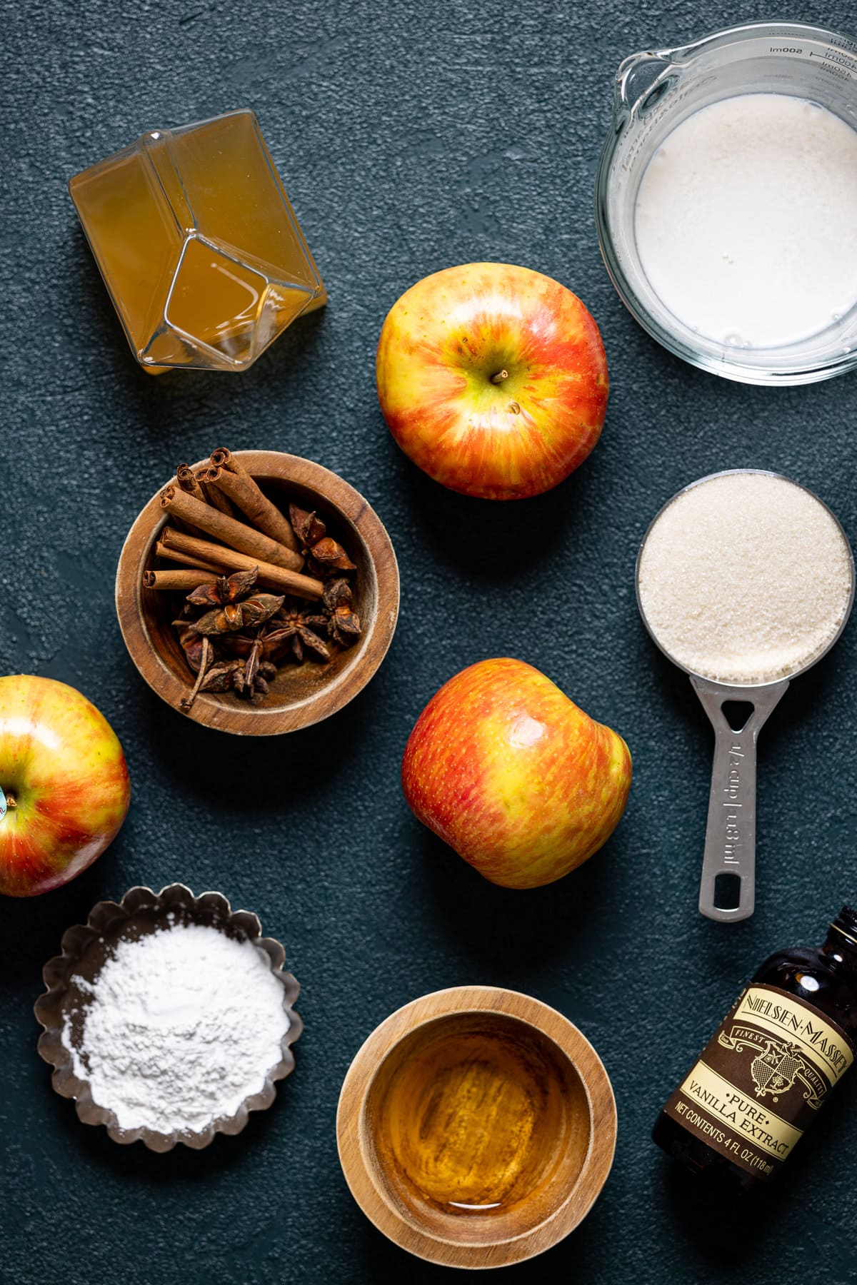 Ingredients for Baked Vegan Apple Cider Donuts including apples, cinnamon sticks, and vanilla extract