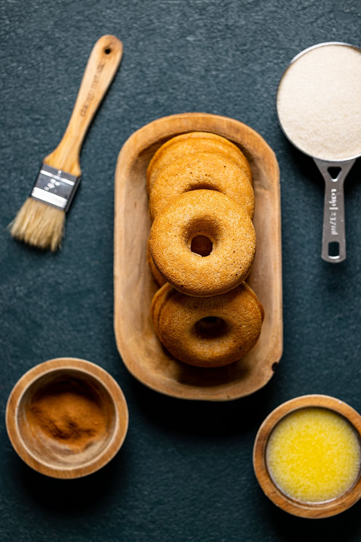 Un-coated Baked Vegan Apple Cider Donuts next to ingredients for the sugar coating