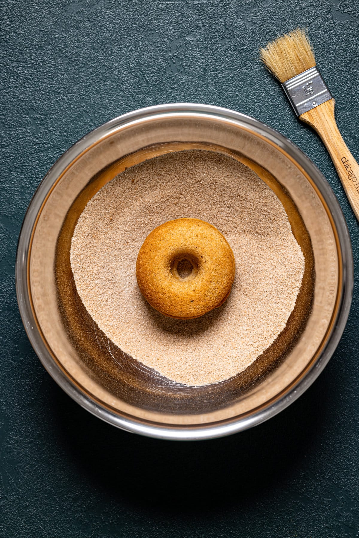 Baked Vegan Apple Cider Donut in a bowl of sugar coating