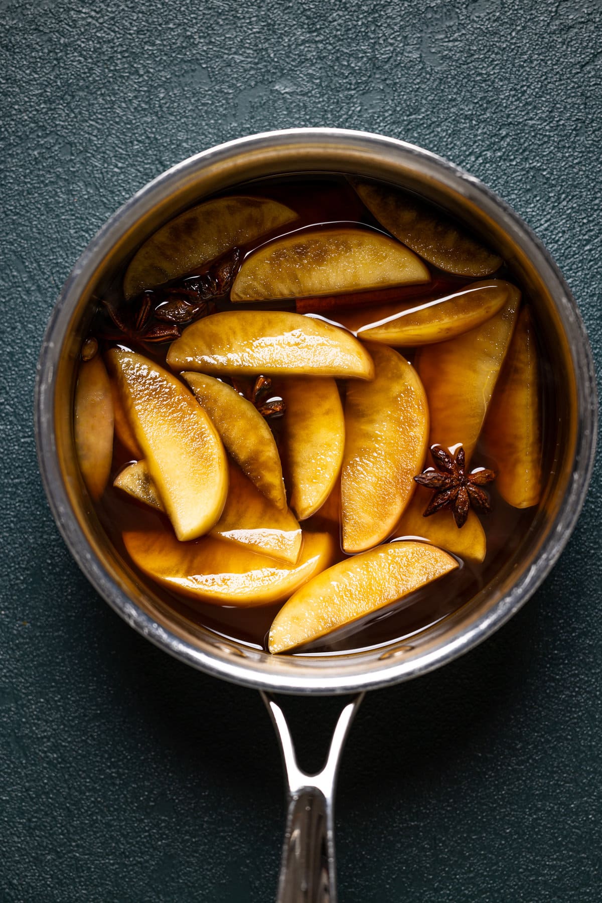Apple slices sitting in a pan with water and spices