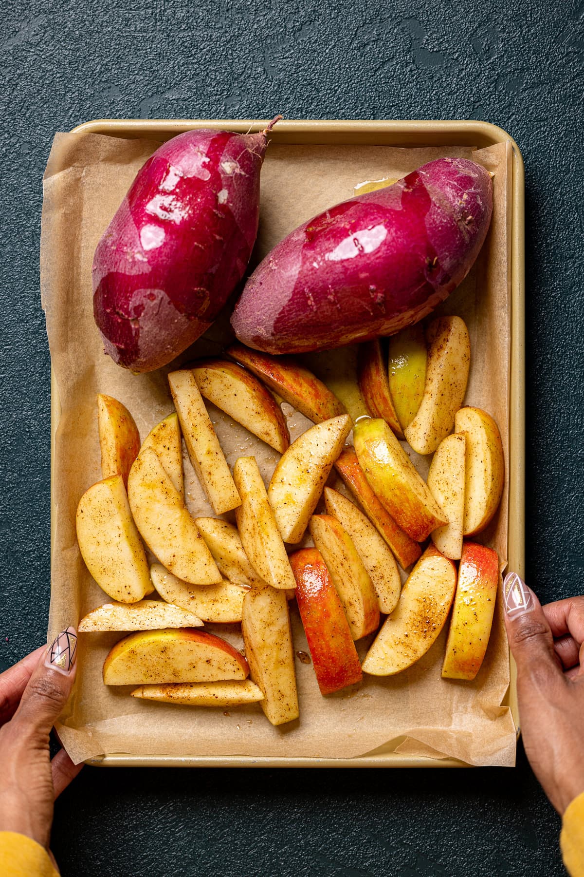 Sweet potatoes and apple slices on a baking sheet