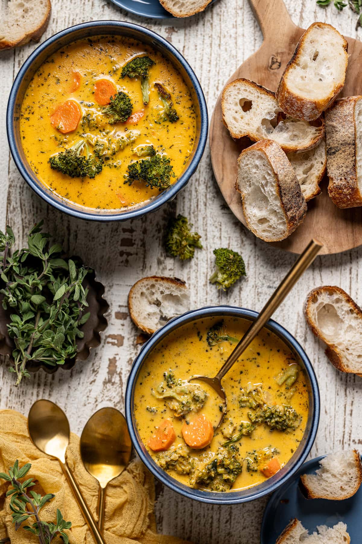 Overhead shot of two bowls of Roasted Broccoli Cheddar Soup next to slices of bread