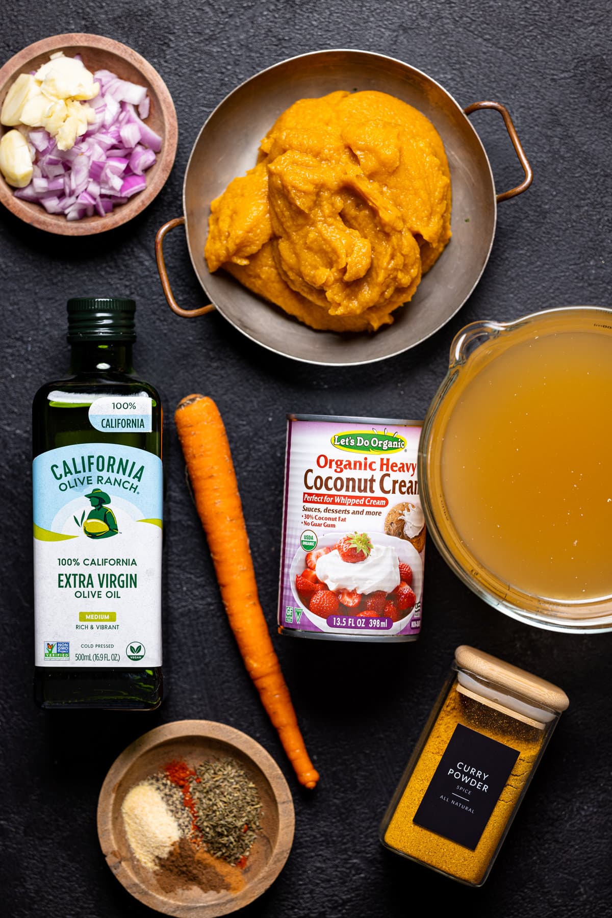 Ingredients for Spicy Curry Pumpkin Soup with Chickpeas including coconut cream, red onion, and carrots