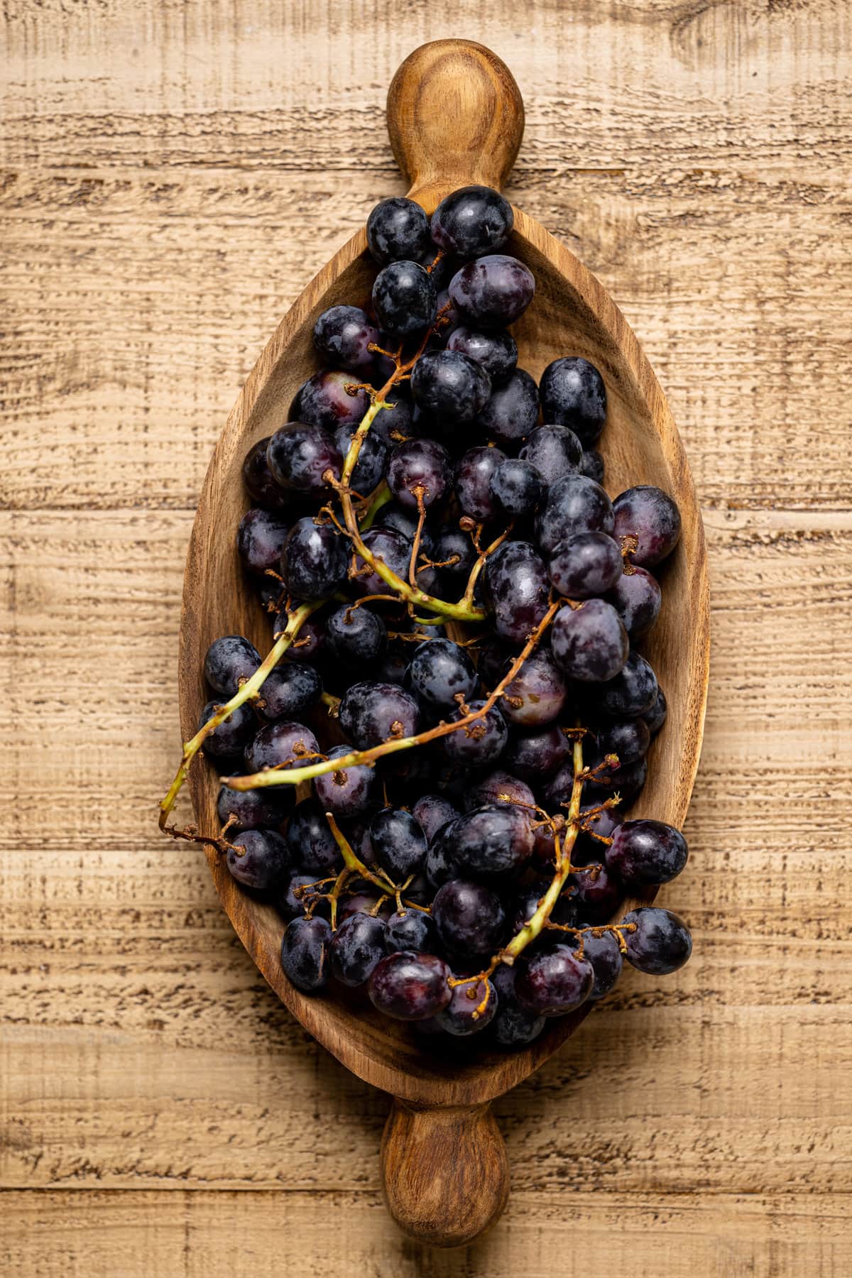 Wooden bowl of black grapes