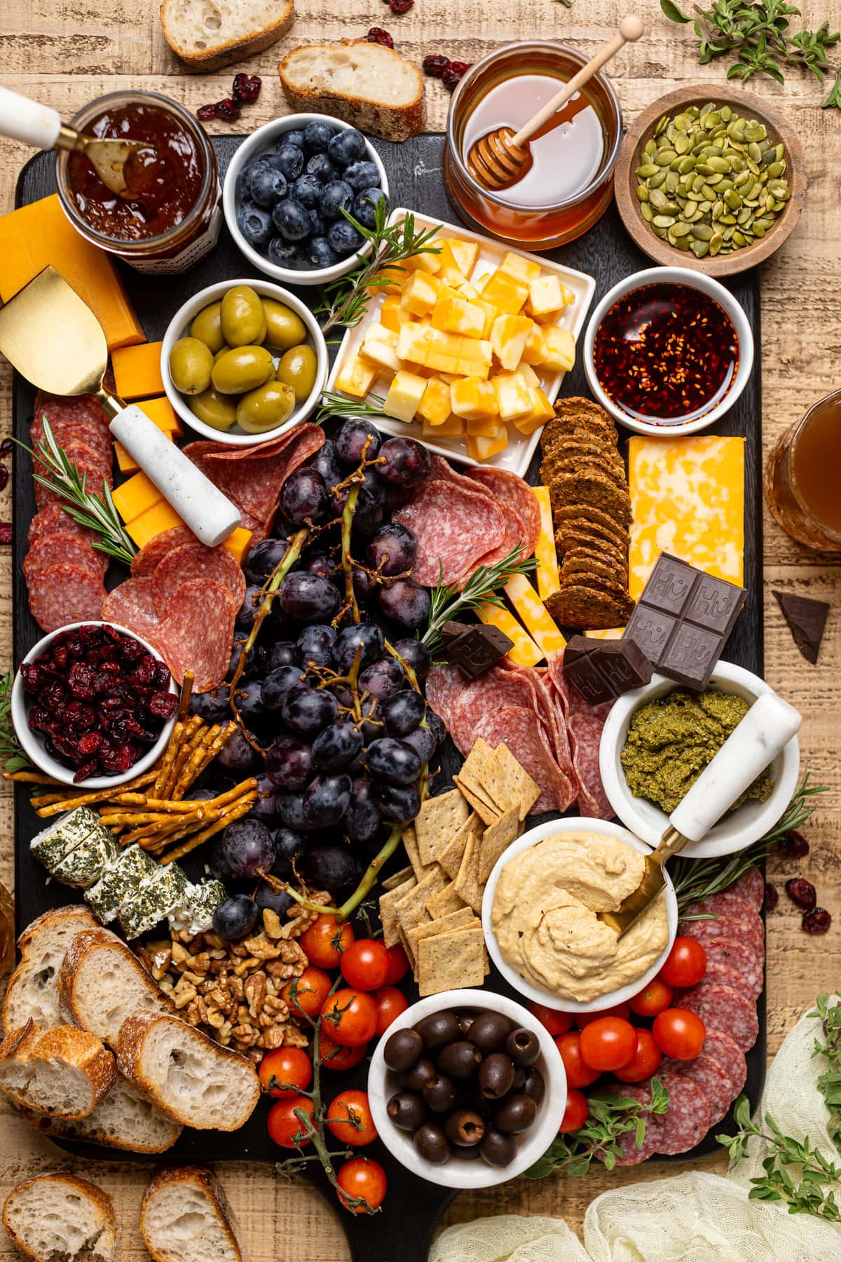 Overhead shot of a colorful and extensive Charcuterie Board including black grapes, green olives, crackers, cheeses, and dips