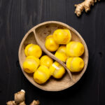 Wooden bowl of Citrus Ginger Turmeric Ice Cubes with Tea