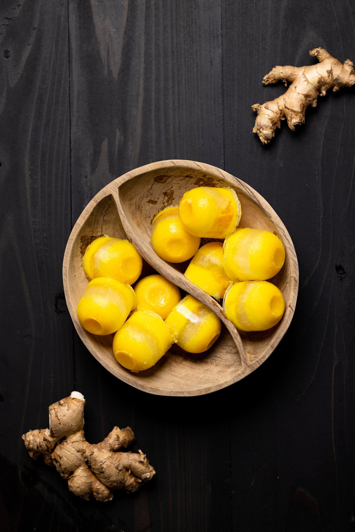 Wooden bowl of Citrus Ginger Turmeric Ice Cubes with Tea