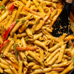 Creamy rasta pasta in a black skillet with a spoon.