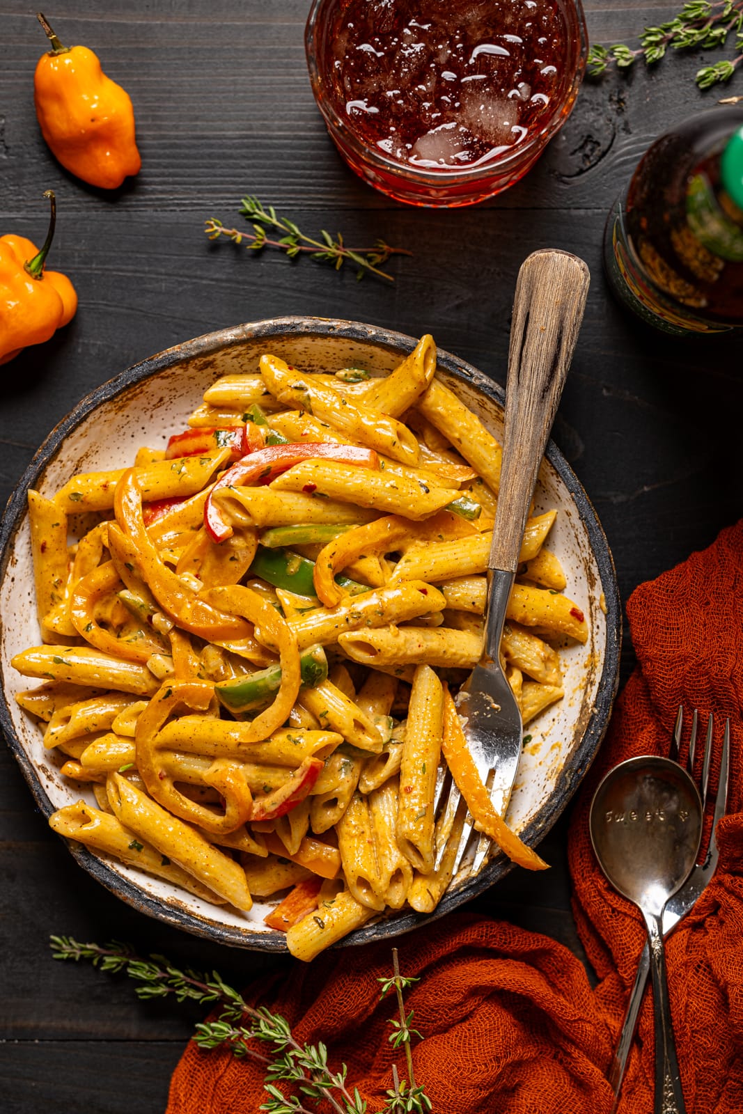 Pasta in a low white bowl with a fork and drink on the side.