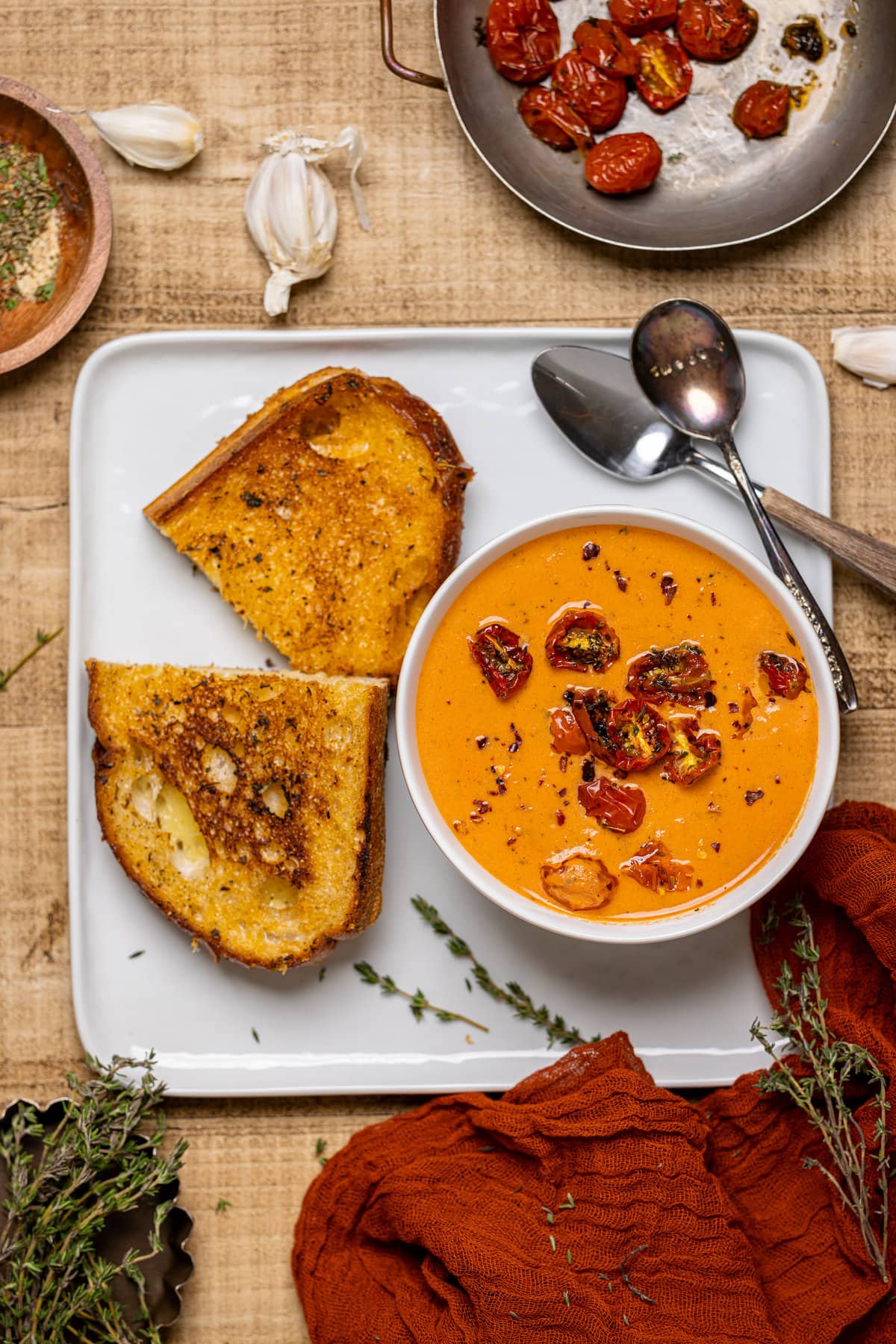 Bowl of Creamy Roasted Garlic Tomato Soup next to a grilled cheese sandwich