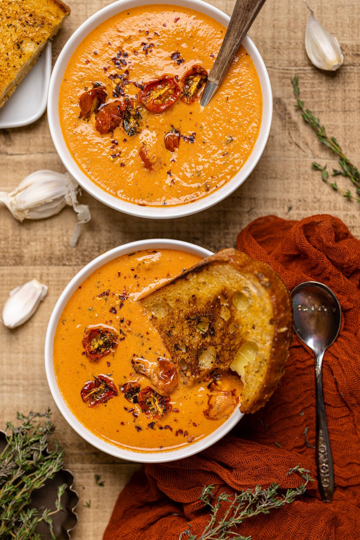 Slice of toast being dipped into a bowl of Creamy Roasted Garlic Tomato Soup