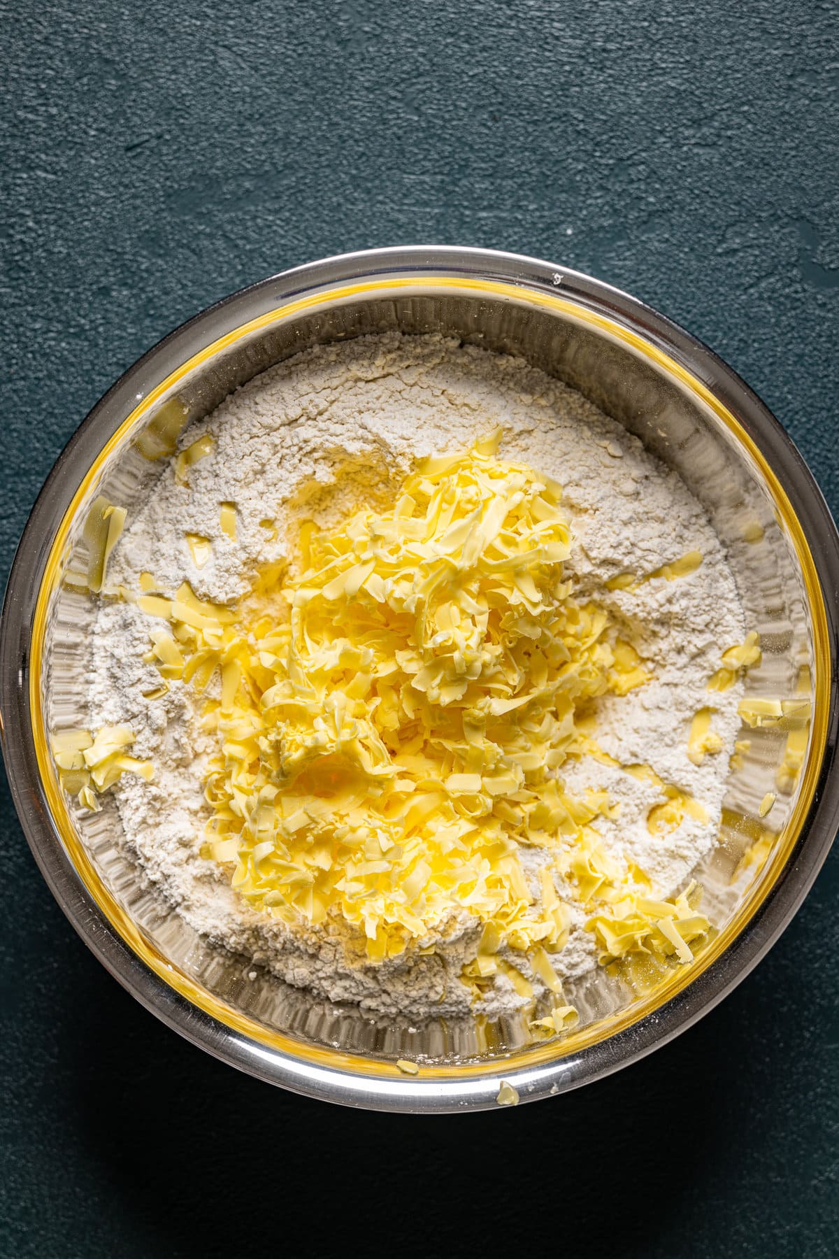 Grated butter on top of dry biscuit ingredients in a bowl