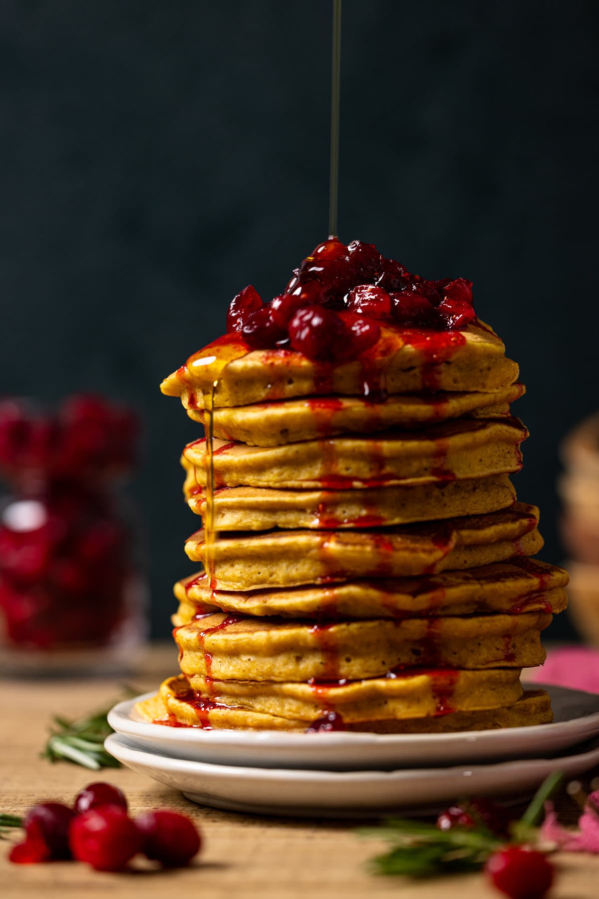 Large stack of Apple Cider Pumpkin Pancakes topped with Cranberries and syrup