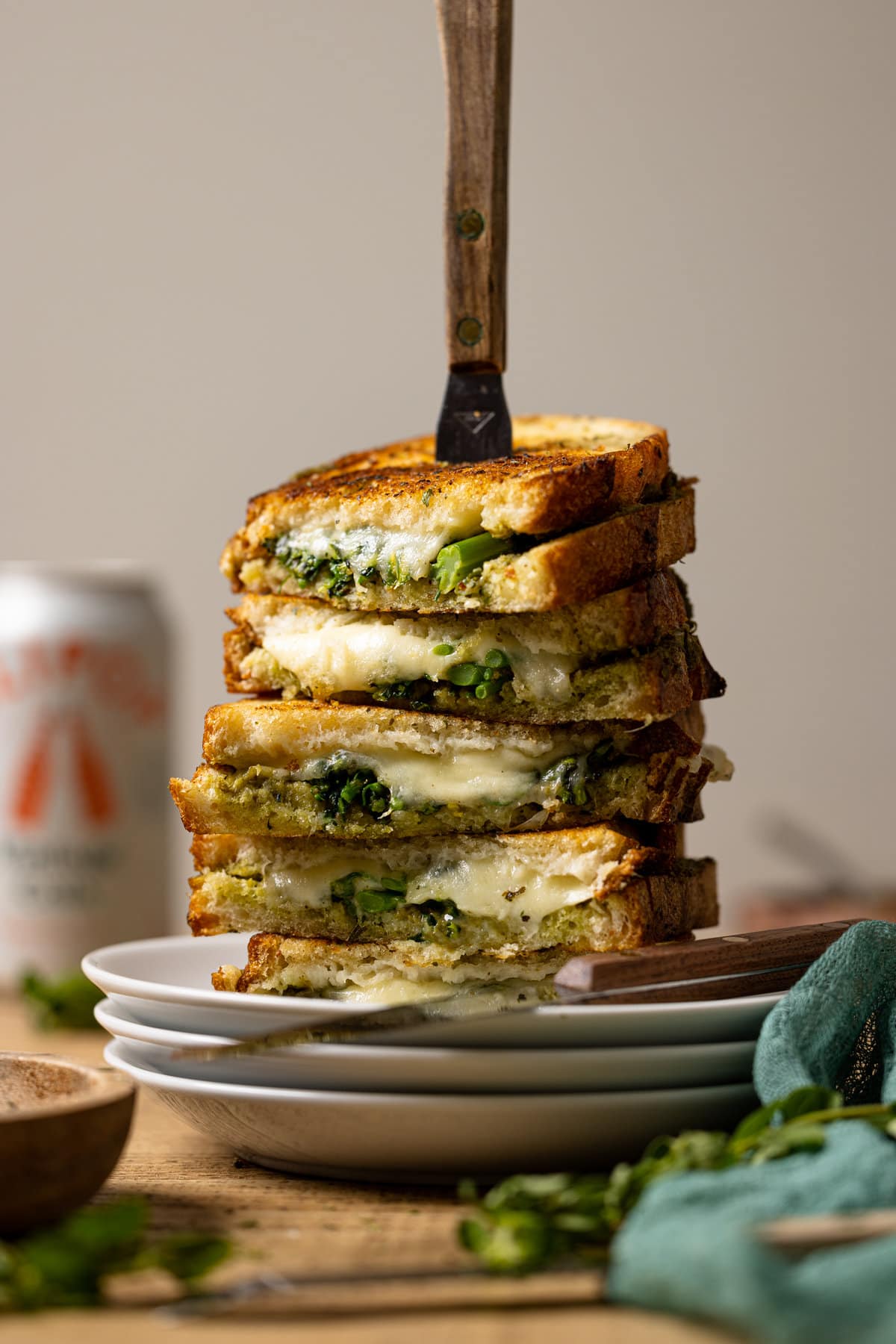 Stack of Broccoli Pesto Grilled Cheese sandwiches skewered with a knife