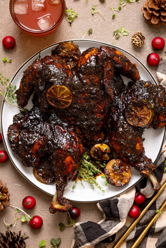 Jamaican Spatchcock Jerk Whole Roast Chicken on a platter with drinks.