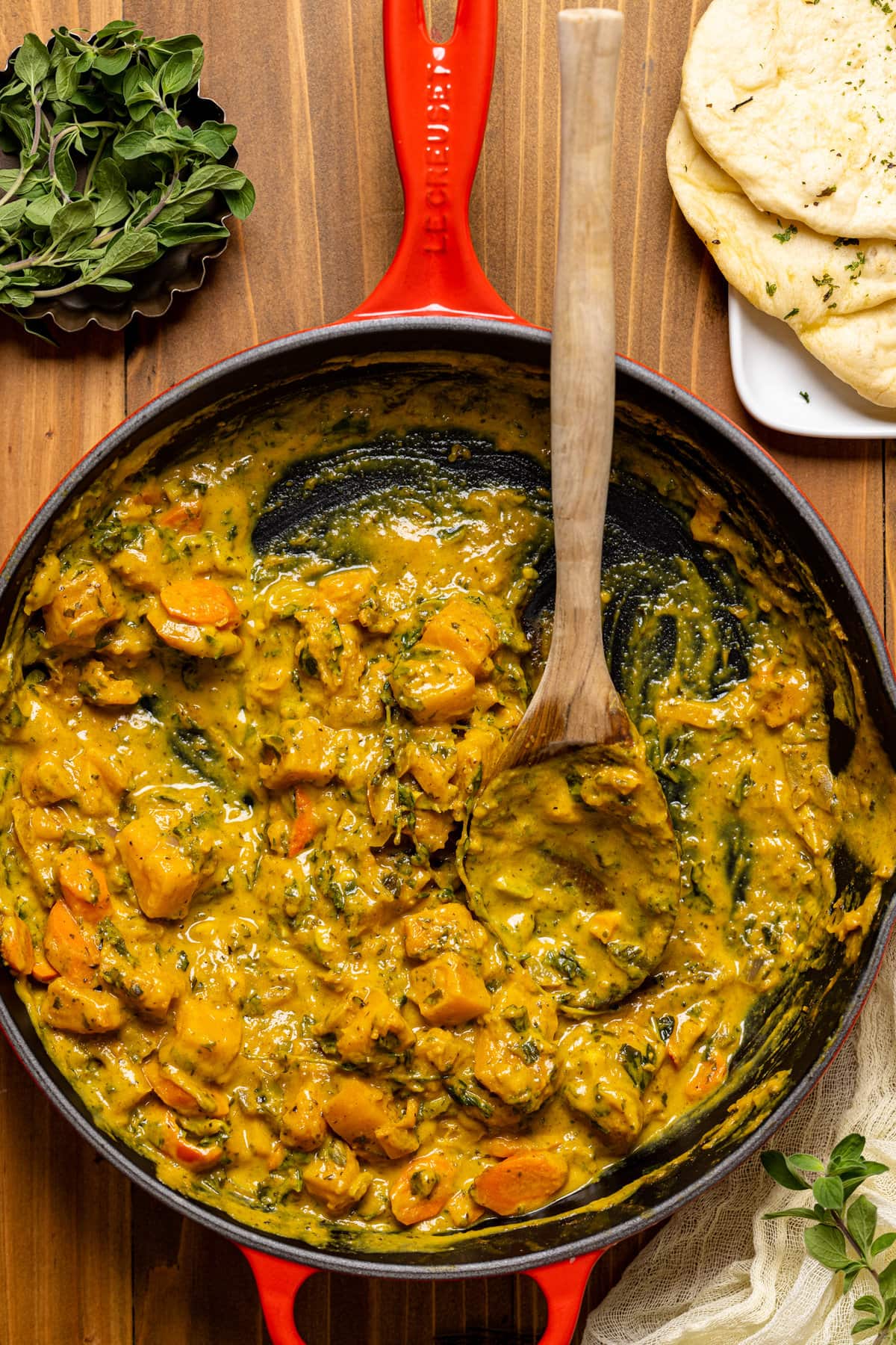 Wooden spoon scooping Vegan Pumpkin Curry Butternut Squash from a skillet