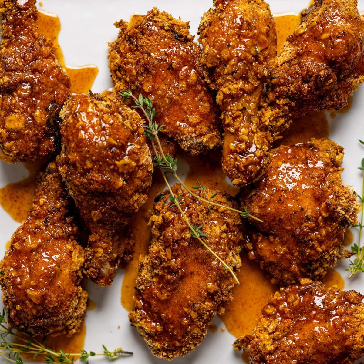 Fried chicken on a white plate with honey sauce on chicken.