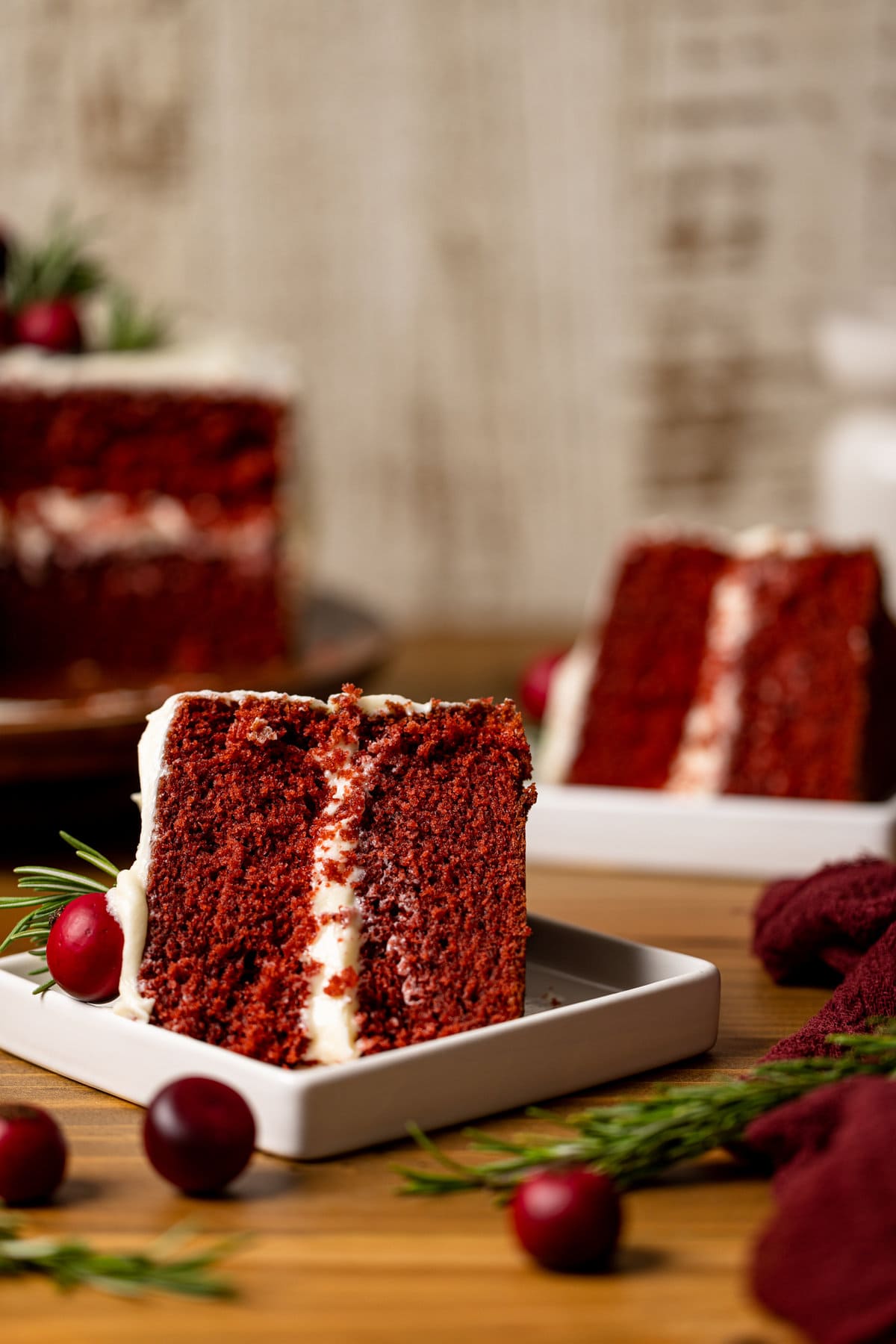 Two slices of Red Velvet Cake with Cream Cheese Frosting on their sides