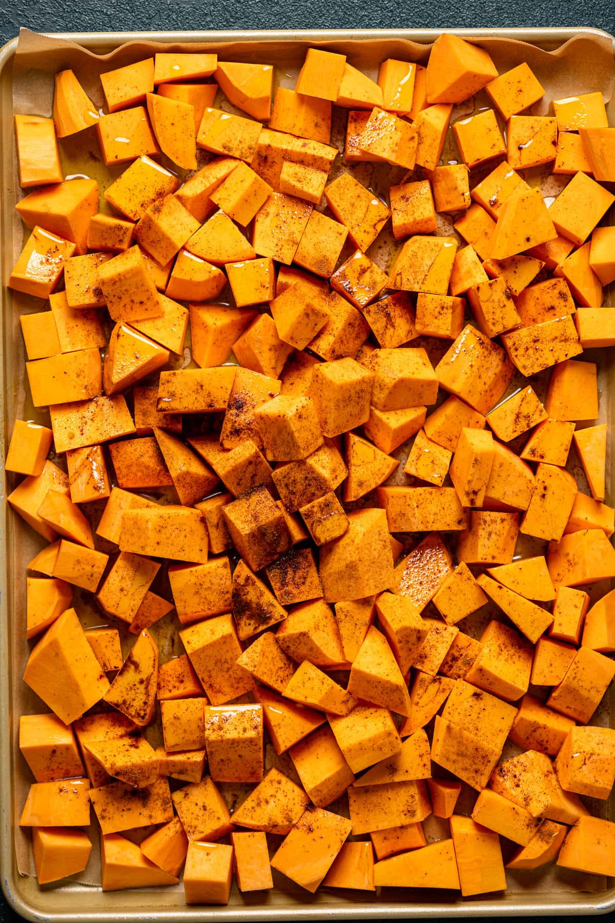 Seasoned, chopped sweet potatoes on a sheet pan