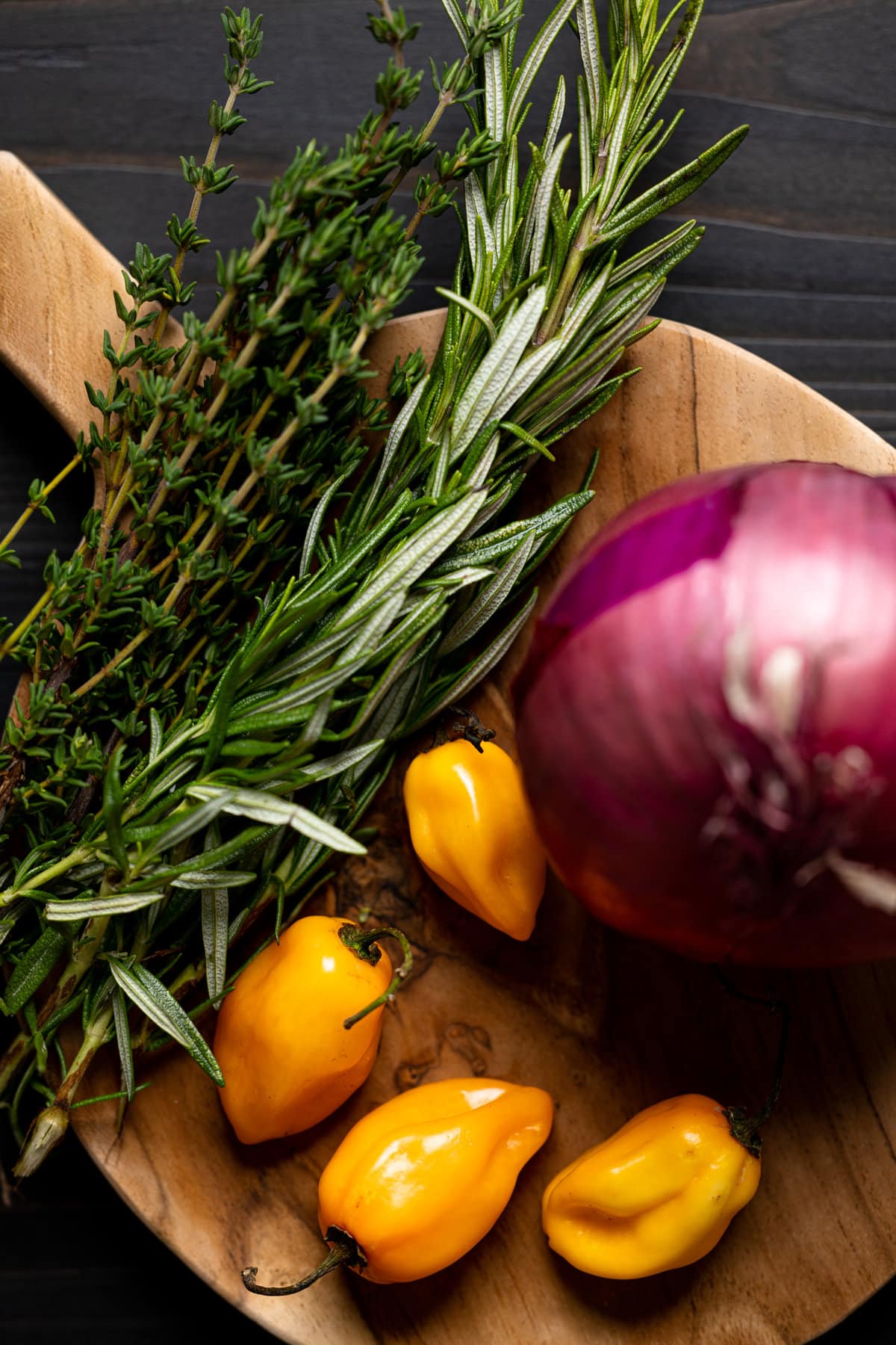 Closeup of a red onion, peppers, rosemary, and thyme