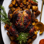 Jerk Whole Roast Chicken on a serving platter surrounded by chopped vegetables