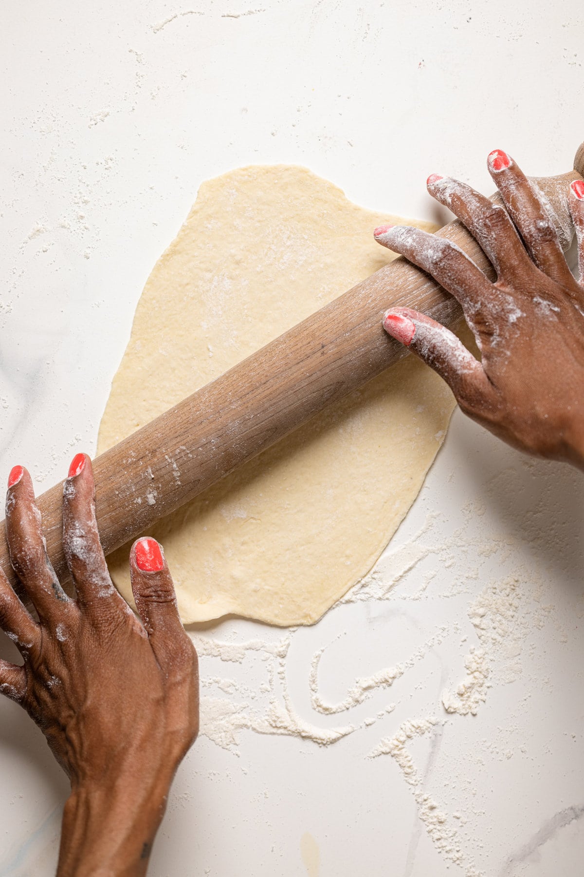 Hands using a wooden rolling pin to flatten Vegan Garlic Naan Bread dough