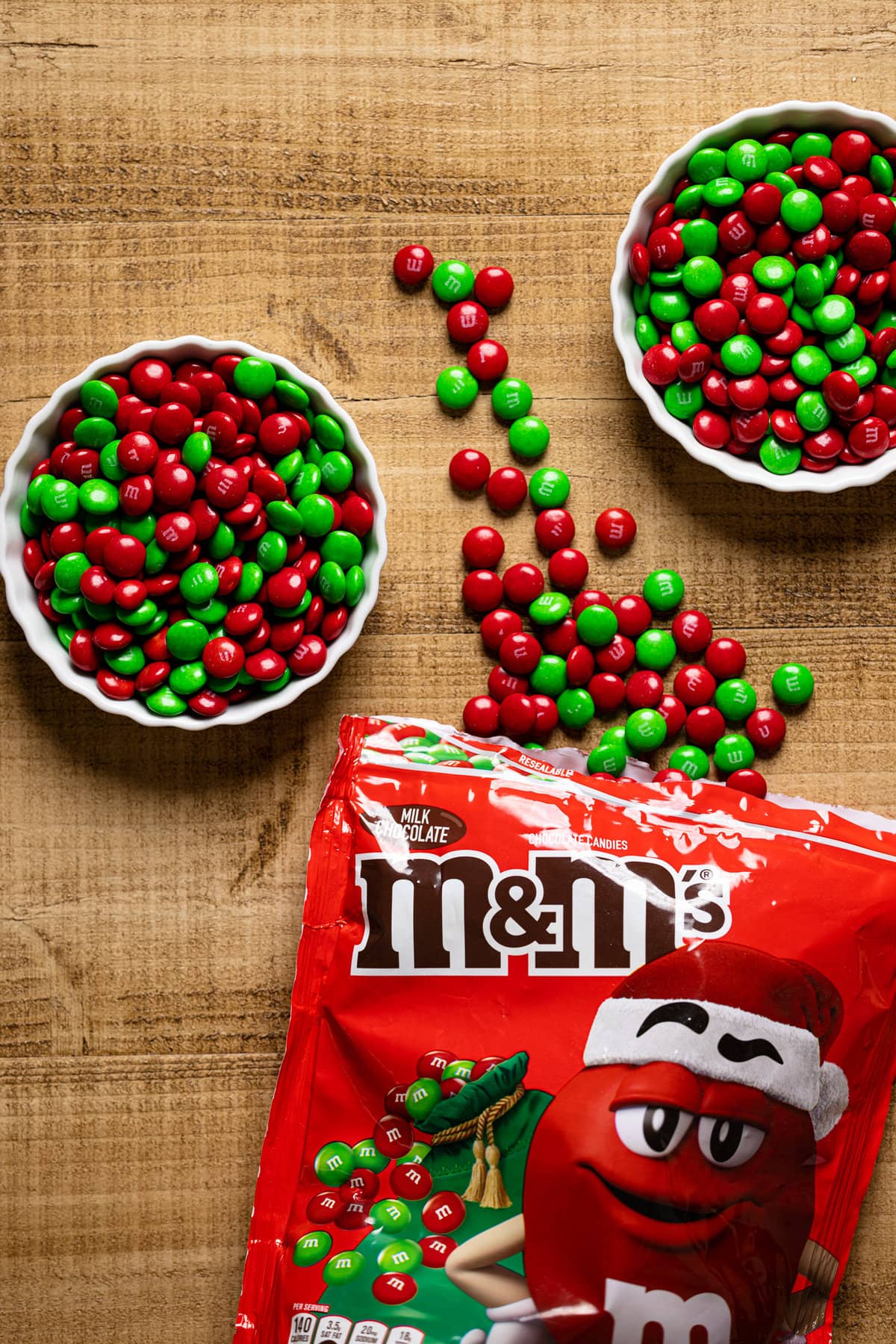 Red and green M&Ms spilling out of a bag and in two bowls