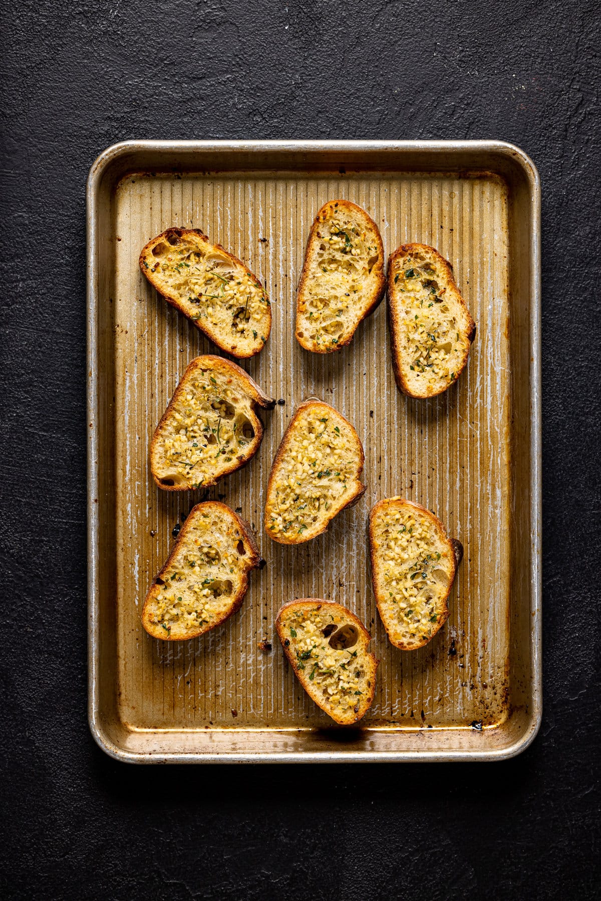 Seasoned, sliced bread on a baking sheet