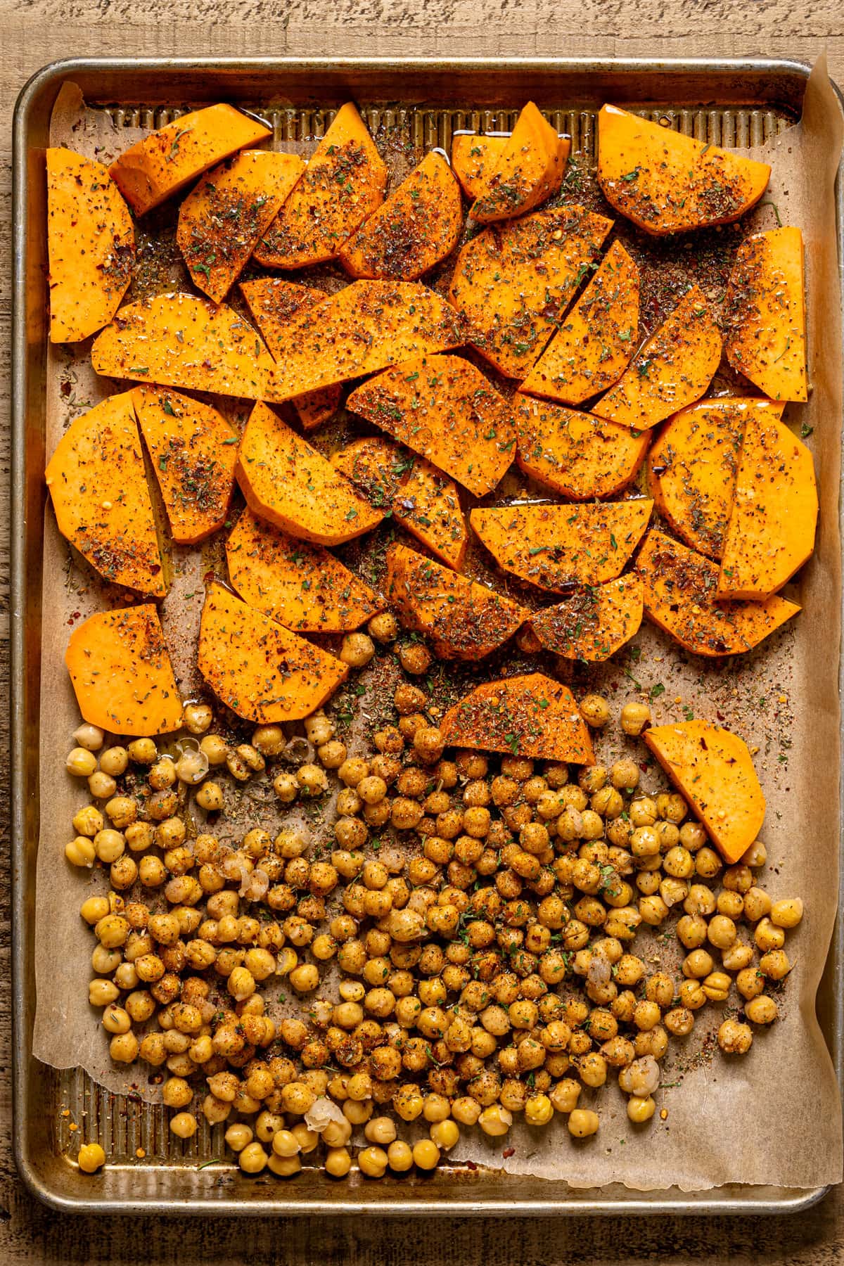 Seasoned sweet potato slices and chickpeas on a baking sheet