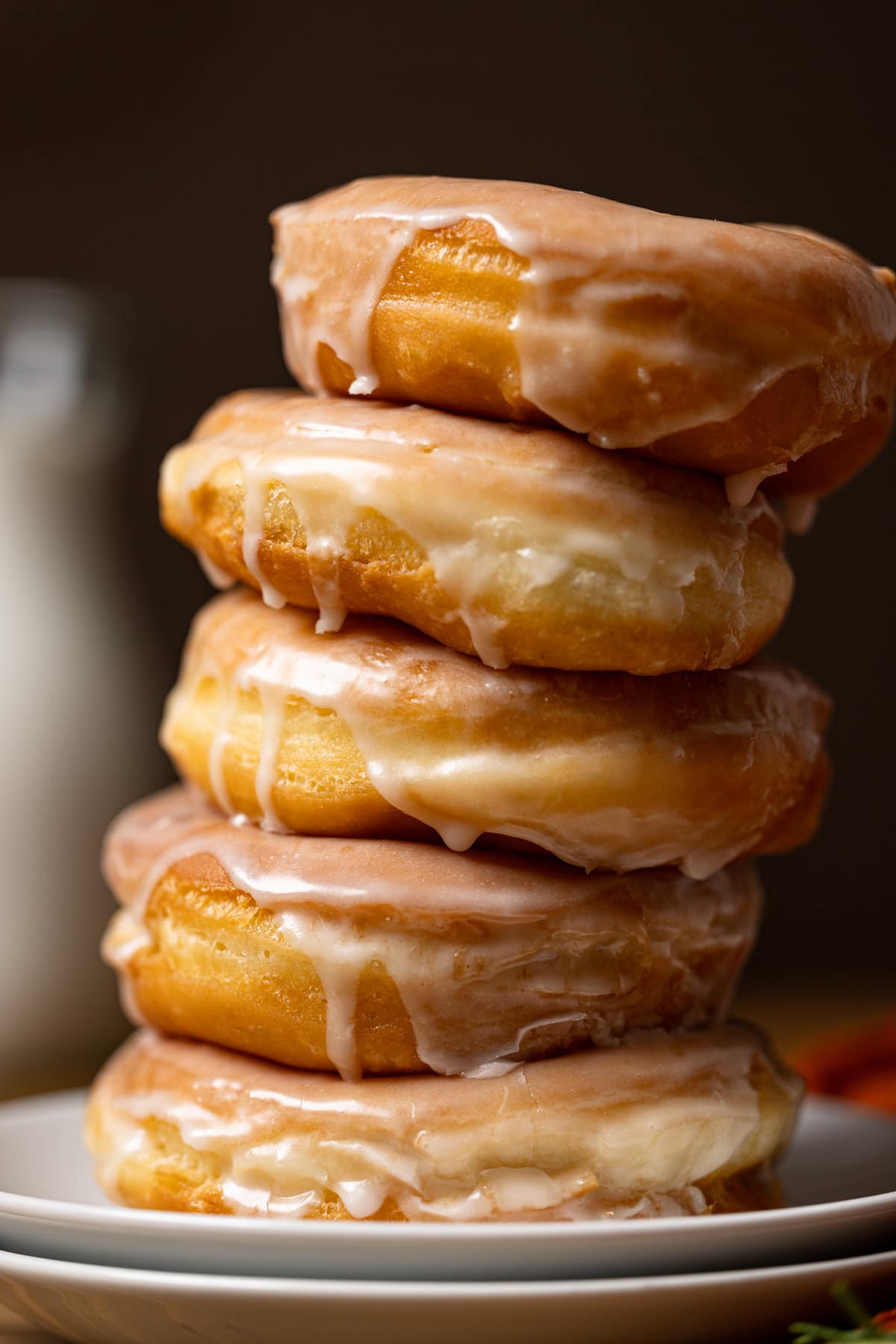 Up close shot of doughnuts stacked on two plates with a dark brown background.