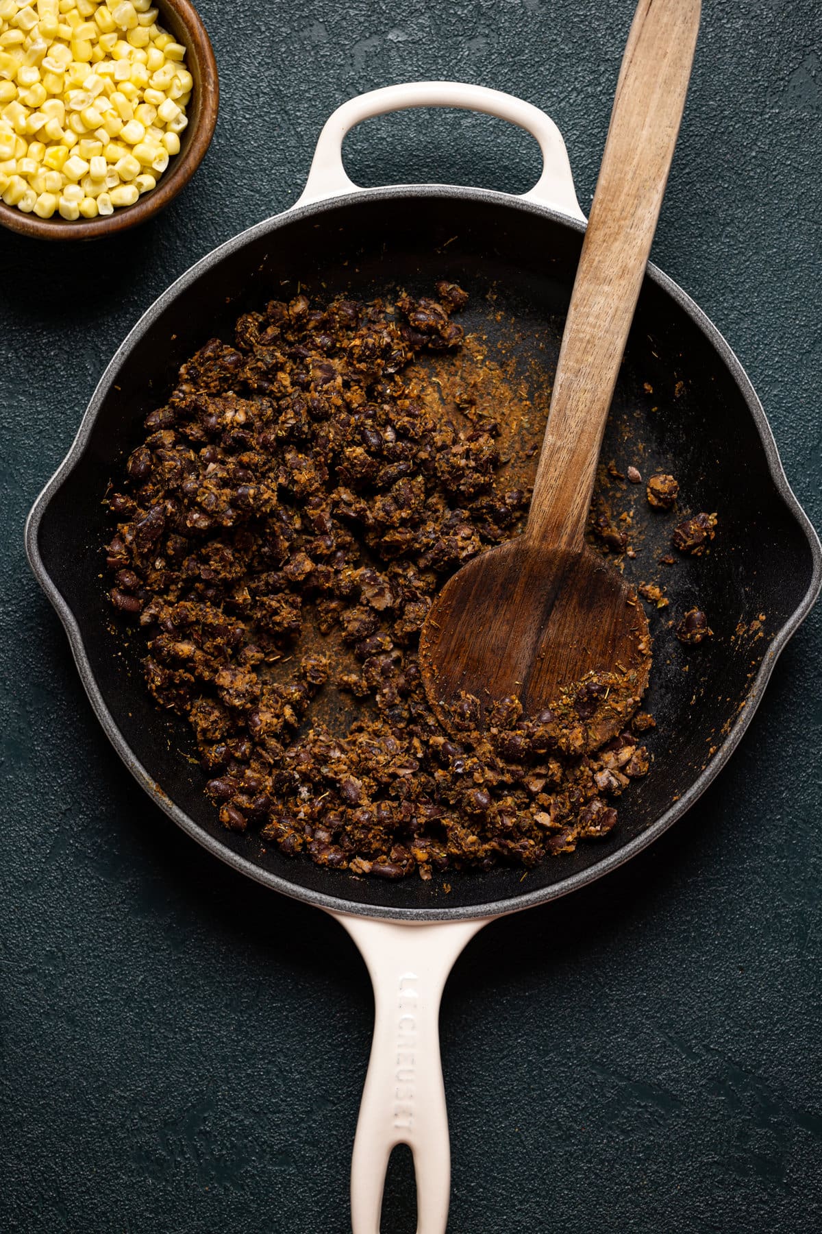 Cooked, seasoned black beans being stirred in a pan