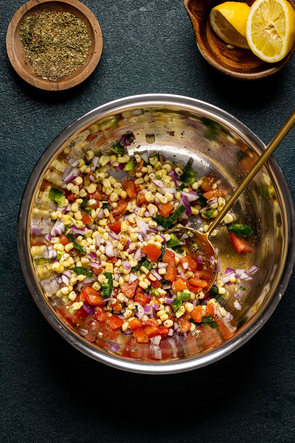 Bowl of colorful ingredients including corn, tomatoes, and red onions