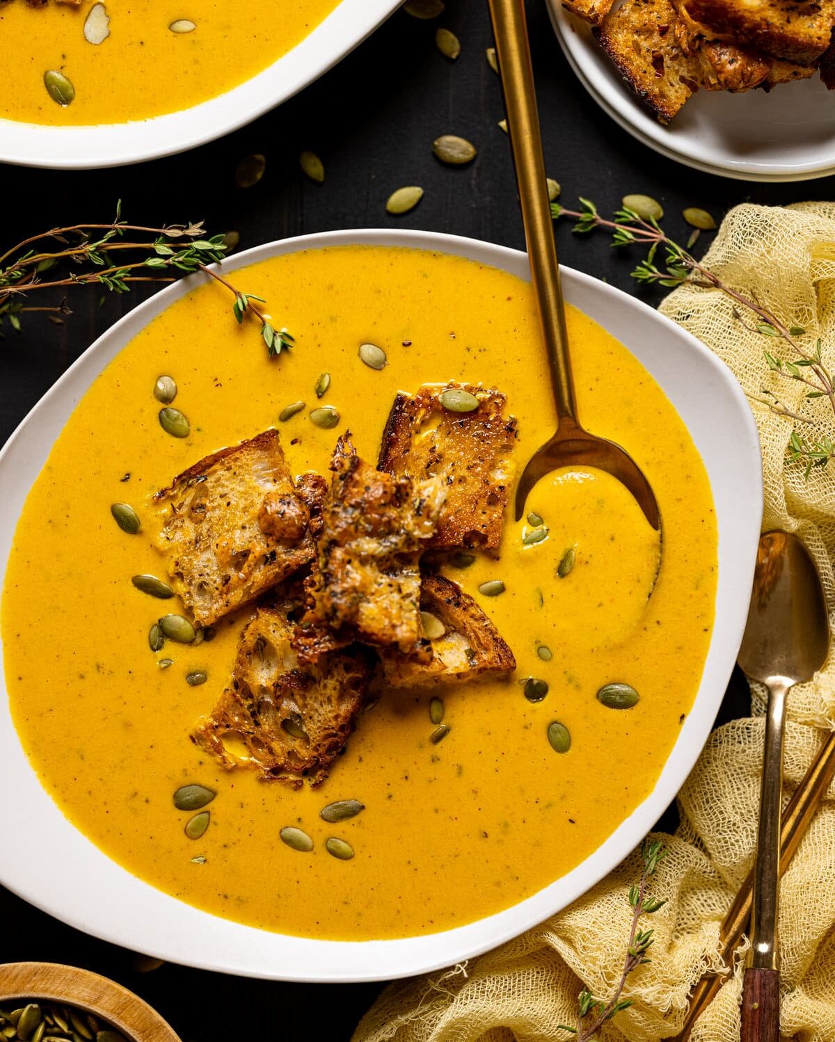 Bowl of Roasted Carrot Soup with Cheesy Croutons with a spoon