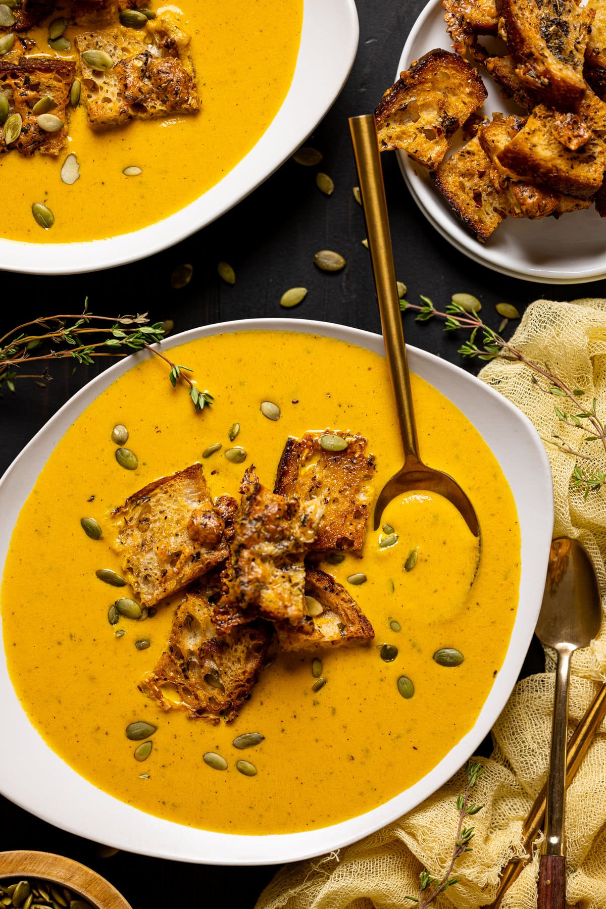 Bowl of Roasted Carrot Soup with Cheesy Croutons with a spoon