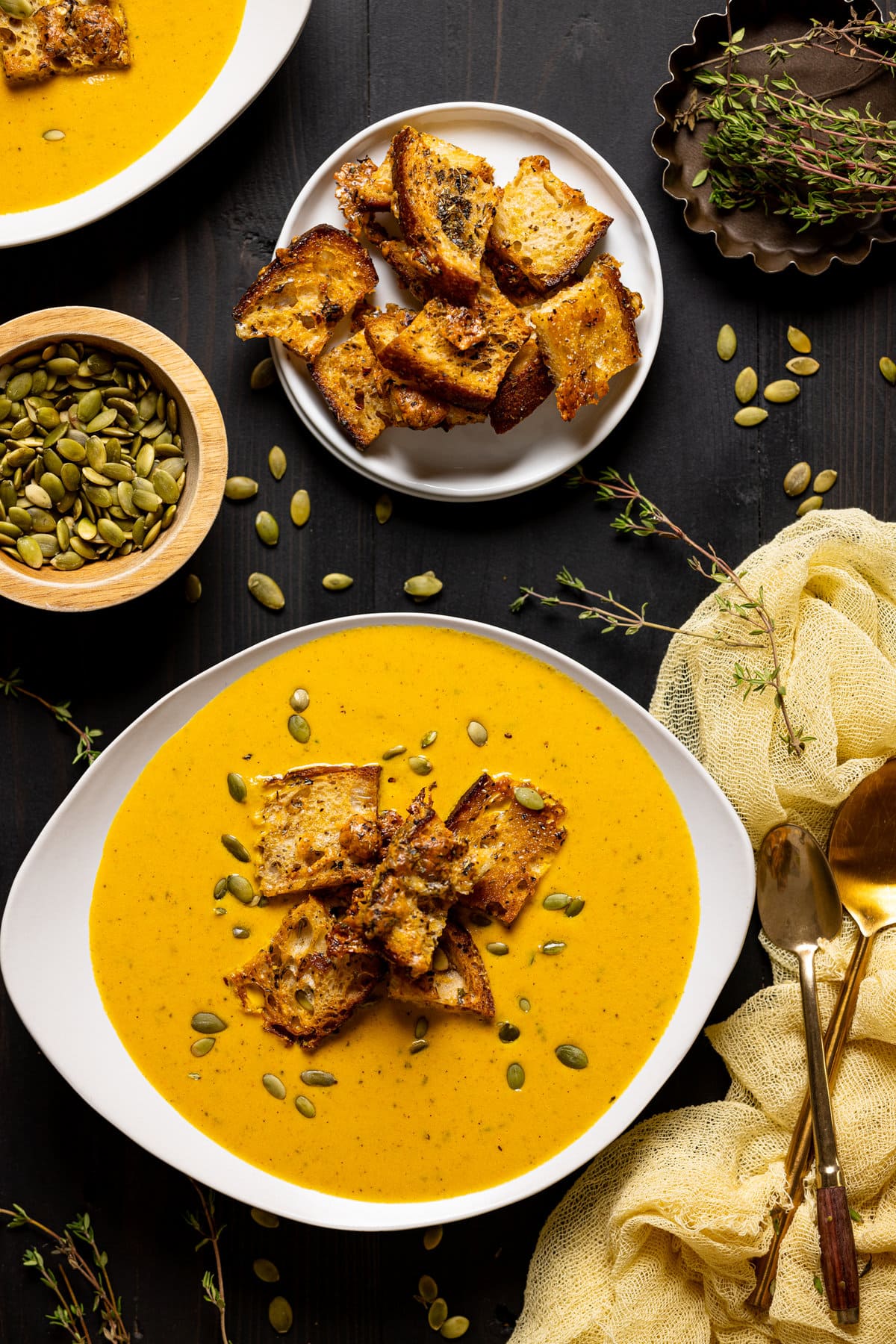 Bowl of Roasted Carrot Soup with Cheesy Croutons next to a bowl of cheesy croutons