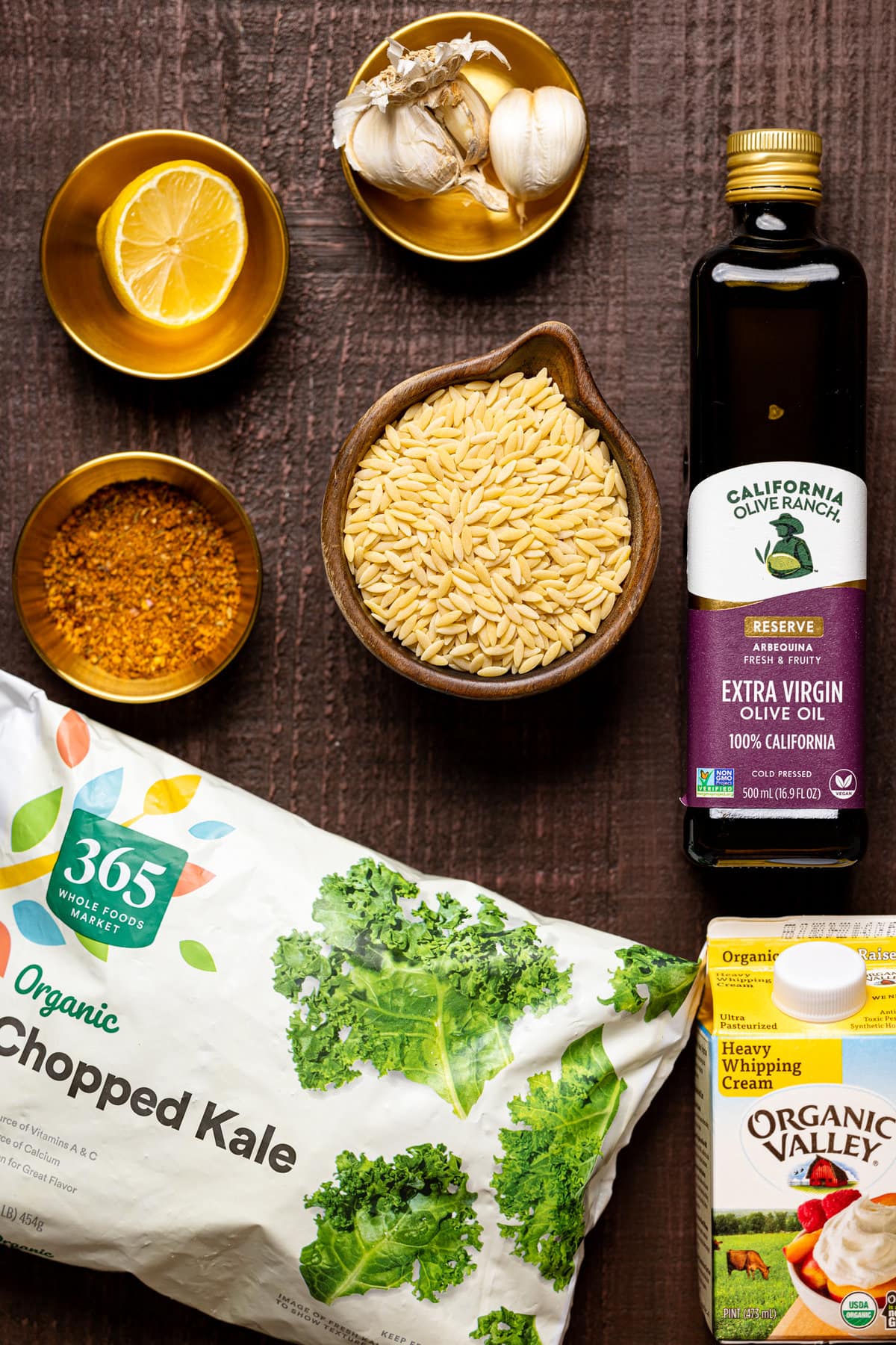 Ingredients for Creamy Cajun Chicken Orzo including kale, heavy whipping cream, and olive oil