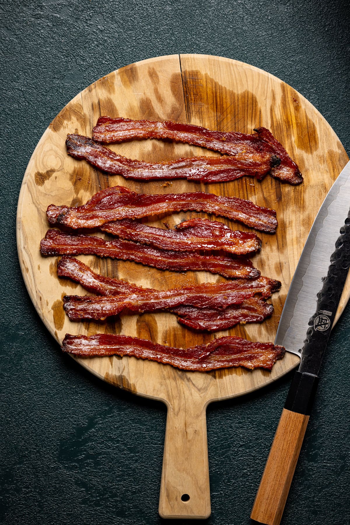 Cooked baken on a pizza paddle with a knife